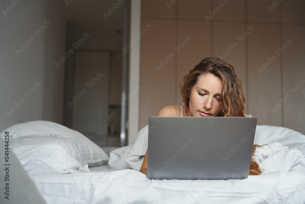 Woman ityping on laptop keyboard in bed after waking up Woman ityping on laptop keyboard in bed after waking up
