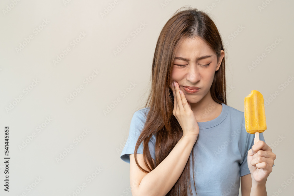 Face expression suffering from sensitive teeth, Asian young woman touching cheek Face expression suffering from sensitive teeth, Asian young woman touching cheek