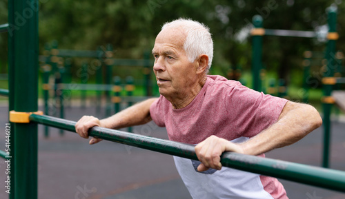 Old man in sportswear exercising push-ups outdoors