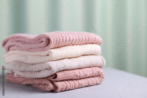 A stack of warm knitted sweaters on a gray background. Selective focus