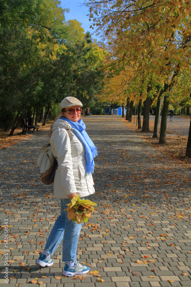 Fototapeta premium Walk in the autumn park with a bouquet of yellow leaves.
