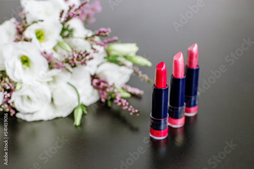 Set of colored lipsticks. Concept of cosmetics and care. Beautiful flowers. Copy space.