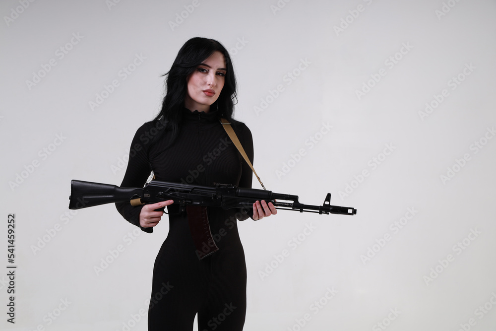 Beautiful slender brunette woman in black clothes with assault rifle Beautiful slender brunette woman in black clothes with assault rifle