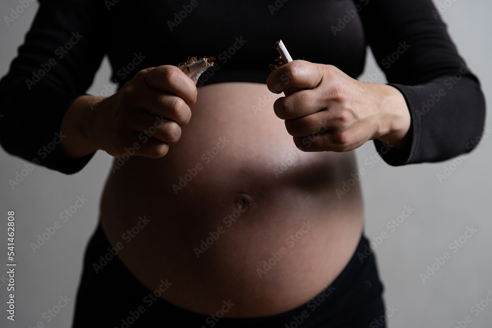 a pregnant woman breaks cigarettes. The concept of the dangers of smoking during pregnancy