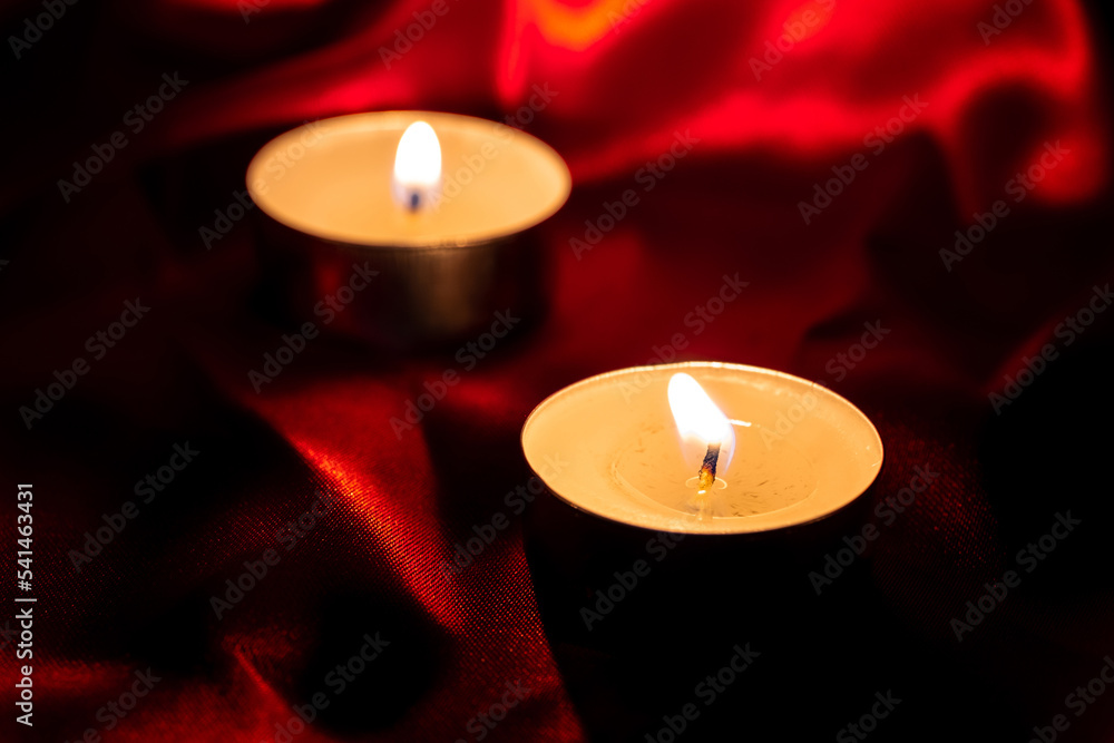 Candle light and red fabric background in the darkness with space for text or image. valentine love concept Candle light and red fabric background in the darkness with space for text or image. valentine love concept