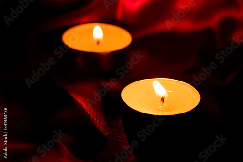 Candle light and red fabric background in the darkness with space for text or image. valentine love concept