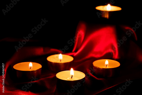 Candle light and red fabric background in the darkness with space for text or image. valentine love concept