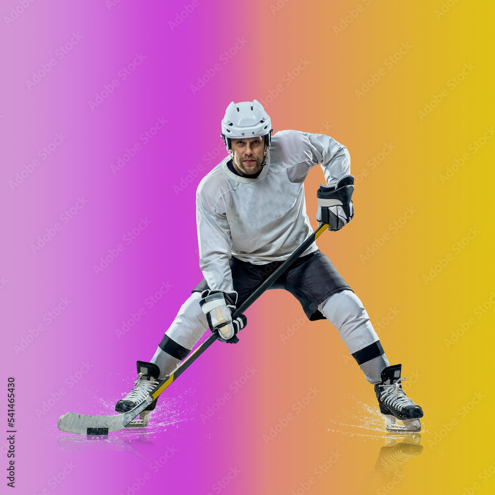 Professional ice hockey player hitting puck for winning goal in action on gradient multicolored neon background. Concept of sport competition. Professional ice hockey player hitting puck for winning goal in action on gradient multicolored neon background. Concept of sport competition.