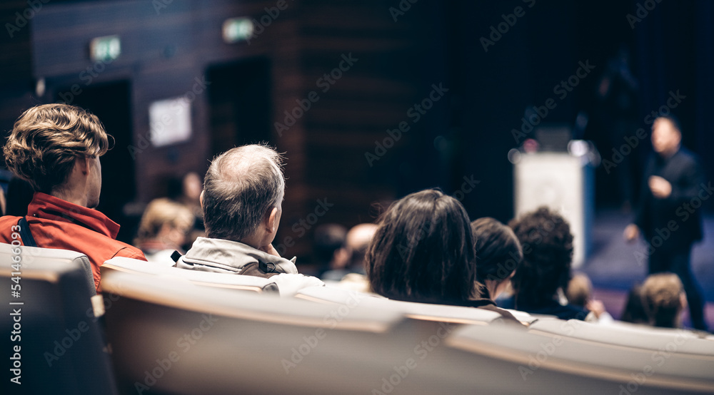 Speaker giving a talk in conference hall at business event. Rear view of unrecognizable people in audience at the conference hall. Business and entrepreneurship concept. Speaker giving a talk in conference hall at business event. Rear view of unrecognizable people in audience at the conference hall. Business and entrepreneurship concept.