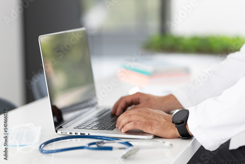 close up of a doctor typing on a laptop computer