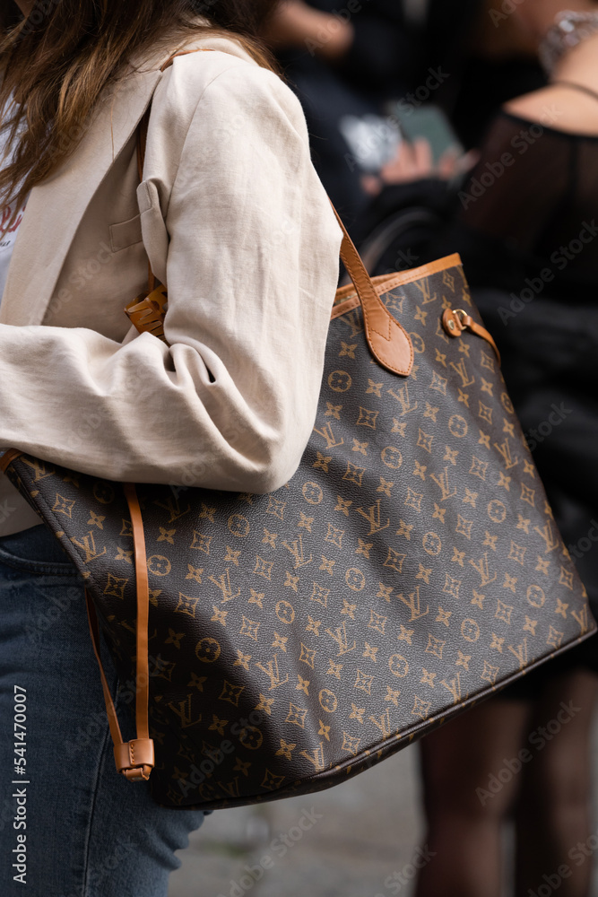 Milan, Italy - September, 21, 2022: Street style outfit detail, woman wears  brown LV monogram print pattern Neverfull handbag from Louis Vuitton foto  de Stock
