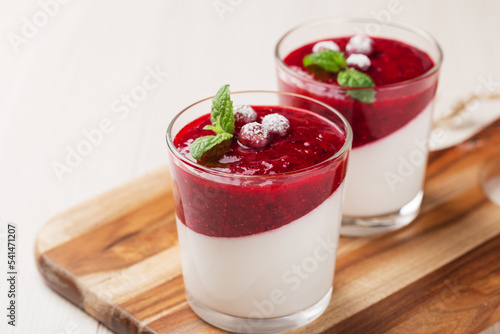 Vegan dairy free coconut Panna cotta with cranberry sauce in glasses on white wooden table. Healthy vegan dessert.