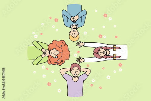 Guys, girls lie on grass among flowers in different directions, look at sky, laugh. Friends spend time at lawn. Top view. Hello spring, summer concept. Vector colorful outline illustration.