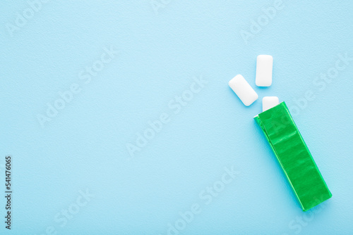 Billede på lærred Opened green pack with white chewing gum pads on light blue table background