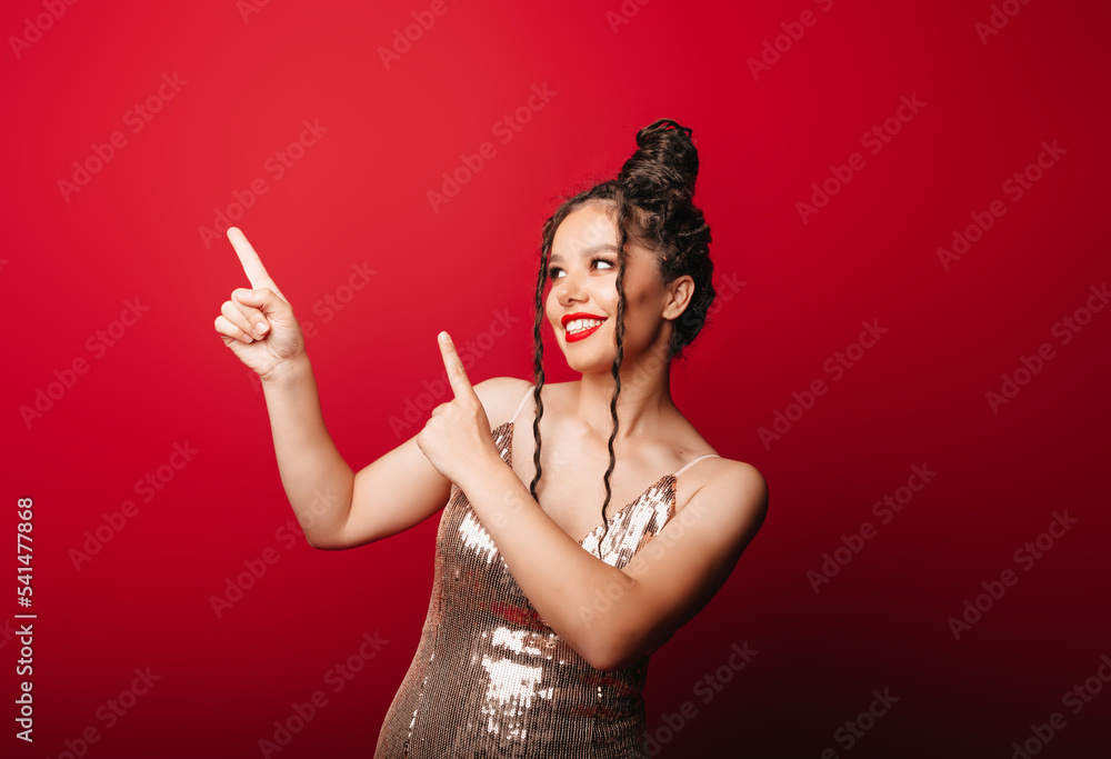 The woman pulls her index finger to the side on a red background, pointing to something on the side of an empty copy space, advertising the advertising concept of the product. The woman pulls her index finger to the side on a red background, pointing to something on the side of an empty copy space, advertising the advertising concept of the product.