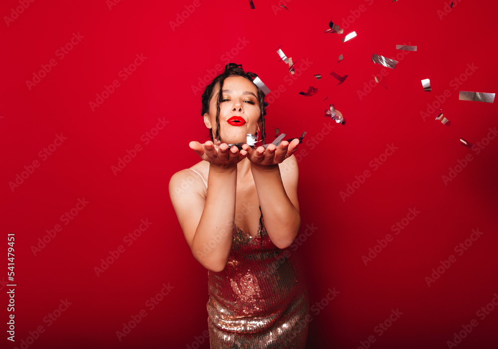 a dream, a dreamy concept. A beautiful, attractive, modern lady with dreadlocks catches confetti, isolated on a red background.holiday and birthday concept a dream, a dreamy concept. A beautiful, attractive, modern lady with dreadlocks catches confetti, isolated on a red background.holiday and birthday concept