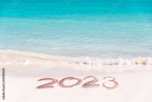 2023 written on the sand of a tropical beach, travel new year card