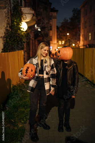 Mom and daughter with Halloween pumpkins  in the evening with lights