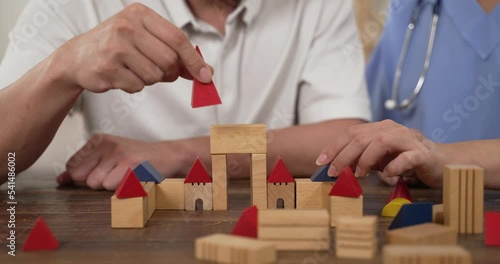 slow motion of selective focus with closeup of color wood bricks being built by trembling hands of an older male patient. Physical treatment for Parkinson’s disease in elderly senior concept