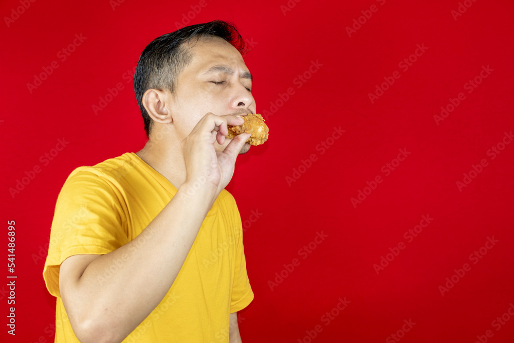 Portrait of Asian young man with fried chicken in hand. Portrait of Asian young man with fried chicken in hand.