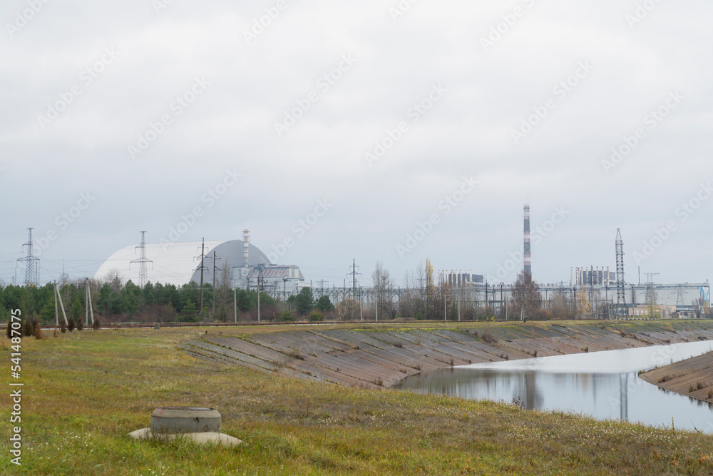 Chernobyl nuclear plant with metal dome over destroyed 4th reactor and famous white and red fireplace 