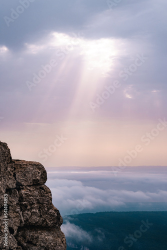 Sunbeams breaking through the clouds and impacting on top of other clouds.