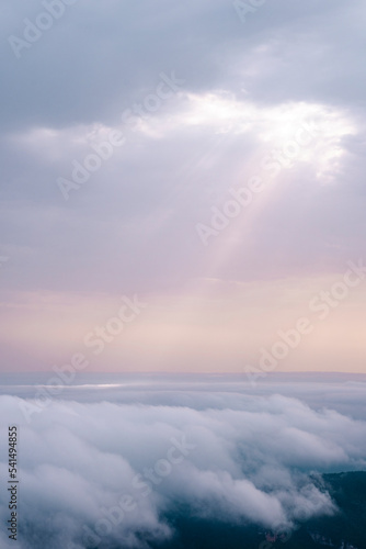 Sunbeams breaking through the clouds and impacting on top of other clouds.