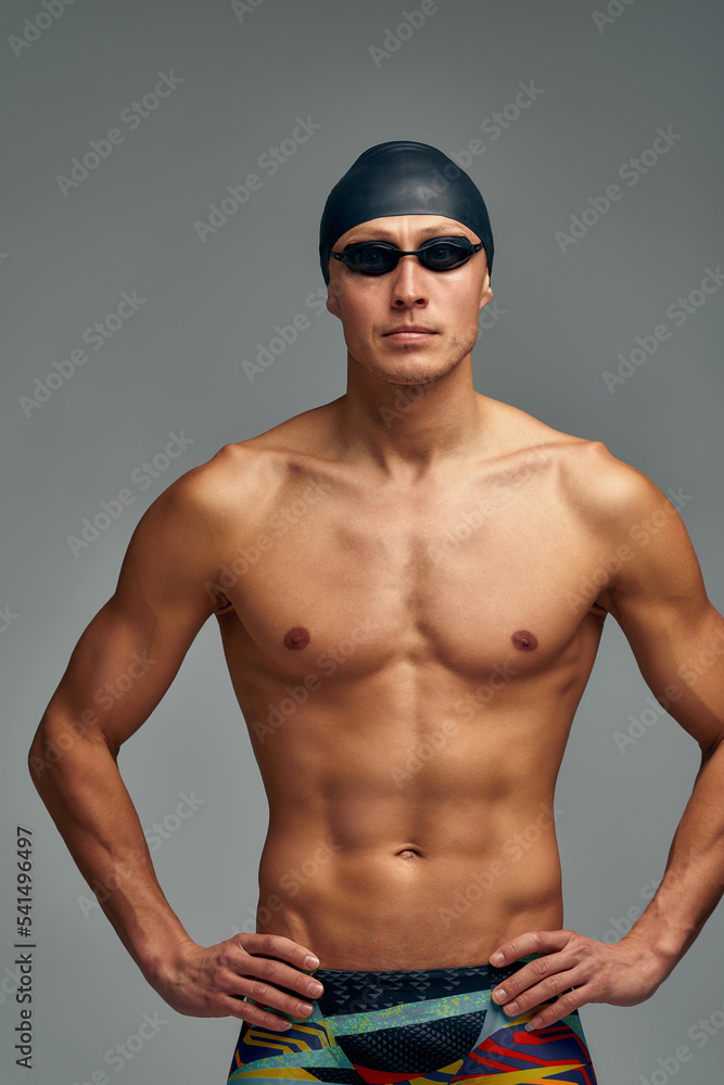 Portrait of a swimmer in a cap and mask, half-length portrait, young athlete swimmer wearing a cap and mask for swimming, copies of space, gray background.