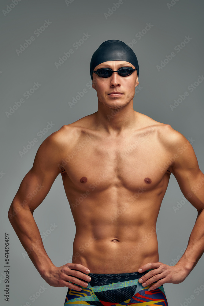 Portrait of a swimmer in a cap and mask, half-length portrait, young athlete swimmer wearing a cap and mask for swimming, copies of space, gray background. Portrait of a swimmer in a cap and mask, half-length portrait, young athlete swimmer wearing a cap and mask for swimming, copies of space, gray background.