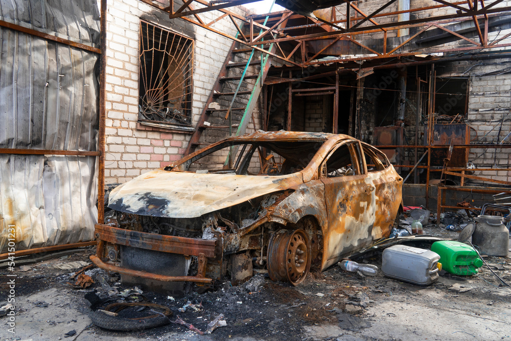 War in Ukraine. 2022 Russian invasion of Ukraine. Countryside. A destroyed burnt-out civilian car stands near a destroyed house. No people. War crimes