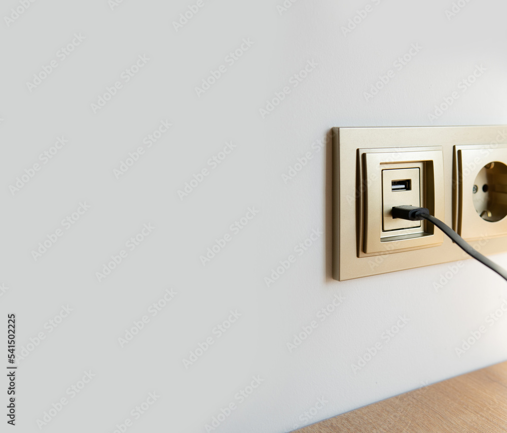 usb charging built into the wall with a wire. wired device charging via usb. charger cord close-up with a blurred background in the socket. usb charging built into the wall with a wire. wired device charging via usb. charger cord close-up with a blurred background in the socket.
