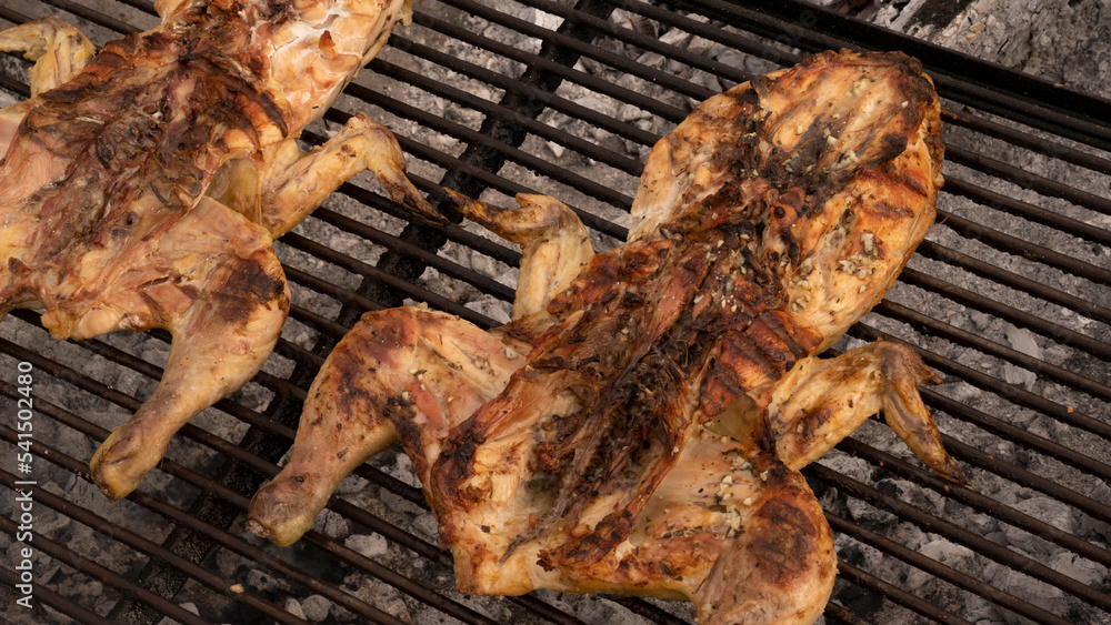 Barbecue outdoor. Roasting a whole chicken in the metal grill with