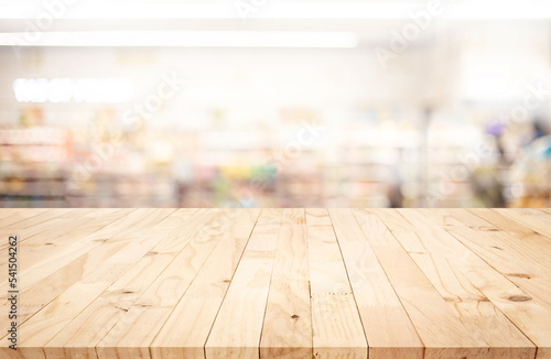 Wood table top on blur of supermarket product shelf background. © hakinmhan