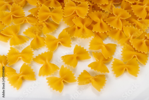 Italian pasta called farfalle, raw macaroni in the shape of bow tie isolated on white, top view