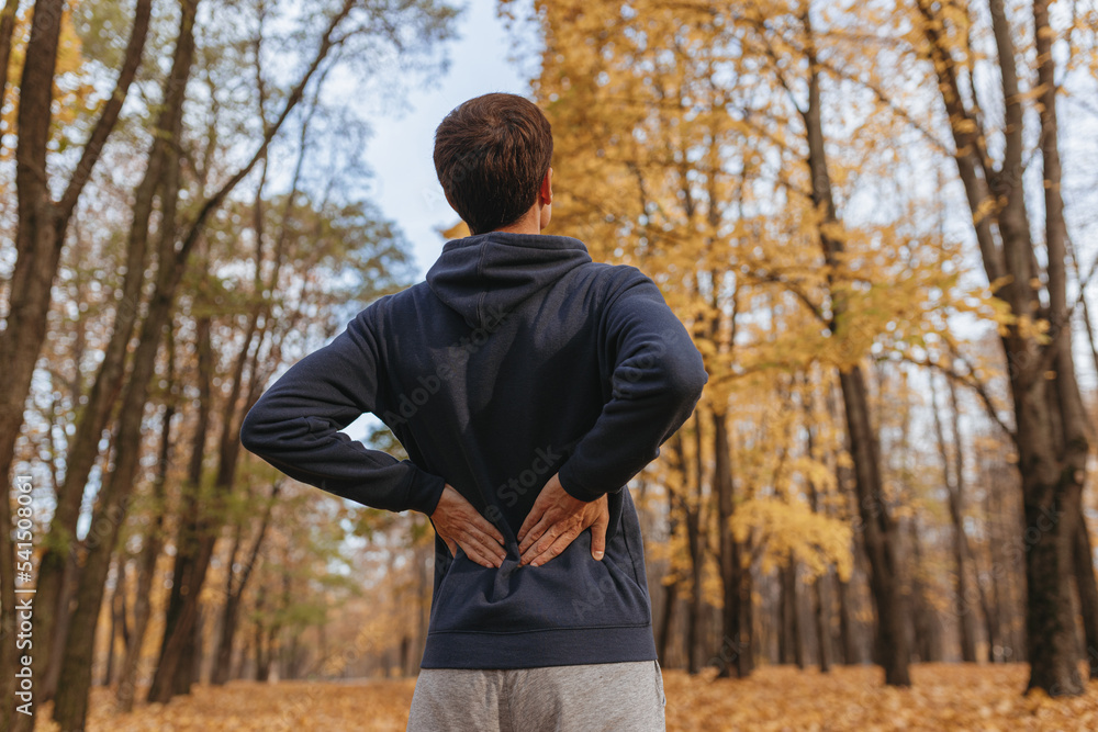 Fototapeta premium Low angle of sportsman stretching back while doing exercise in autumn park and training outdoors