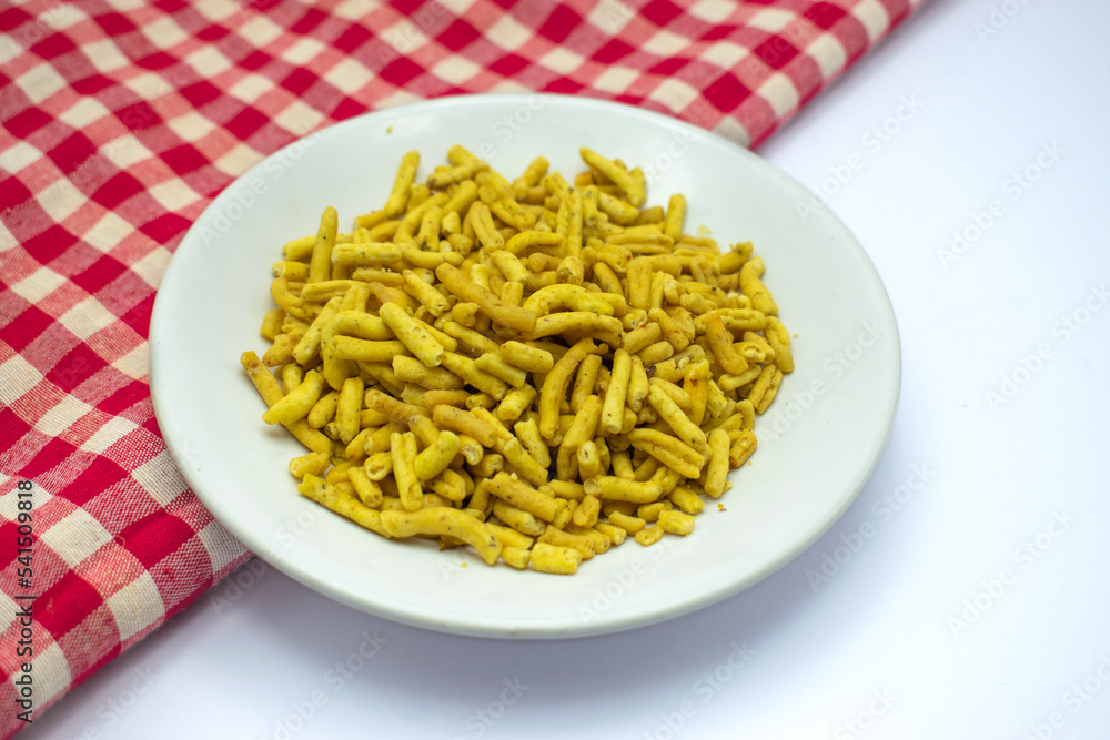 Popular Ratlami Sev in white plate isolated on white background over the red and white checks cloth Popular Ratlami Sev in white plate isolated on white background over the red and white checks cloth