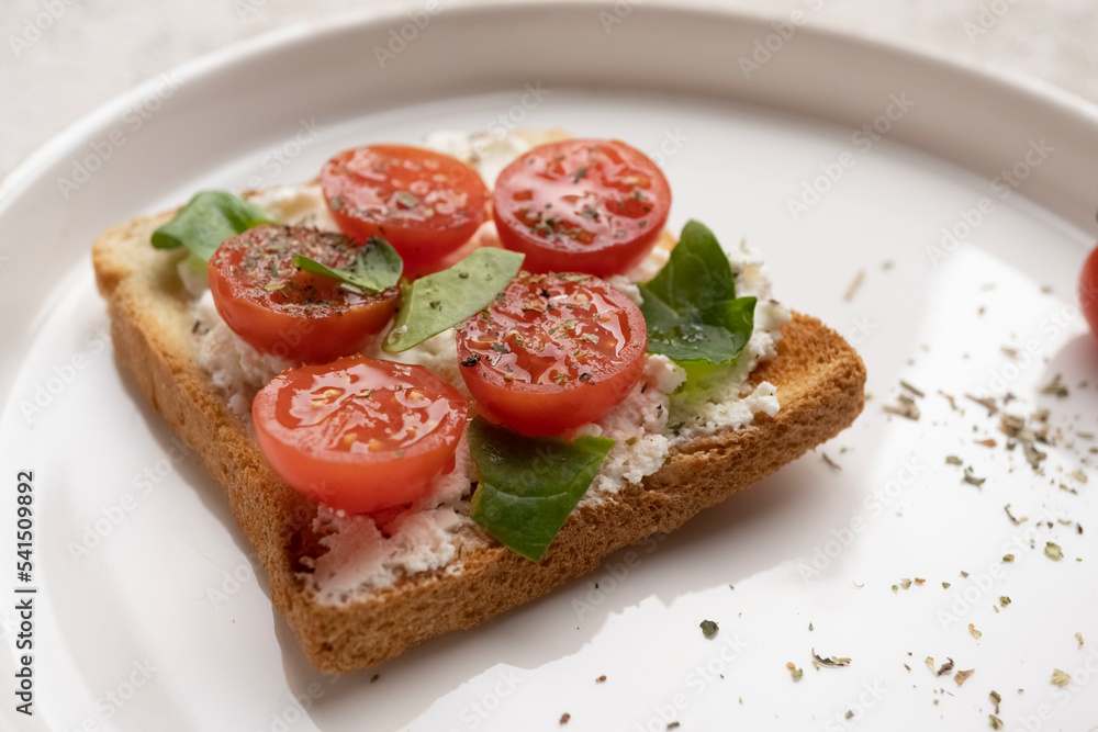 toasts with feta cheese and cherry tomatoes on a white dish, close-up, healthy snack
