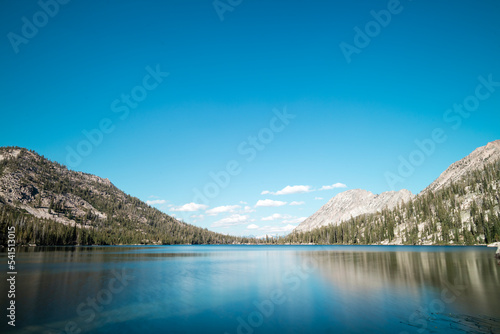 Toxaway Lake, located in Idaho’s Sawtooth Wilderness seen on a summer day, with a blues sky, white clouds and a reflection in the calm waters of the pristine alpine lake. © Silverman Media 
