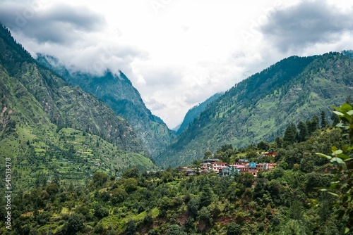 View of a small town surrounded by green mountains. Kasol, India.