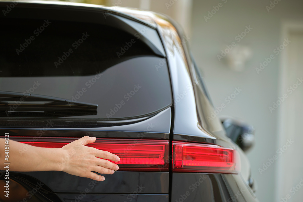 Close-up of human hand on rear car stoplight, checkout before driving. Safety travel concept