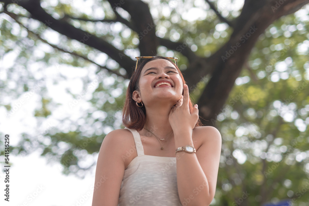 A beautiful stolen shot of a smiling and carefree Asian lady outside the park on an early morning. A beautiful stolen shot of a smiling and carefree Asian lady outside the park on an early morning.