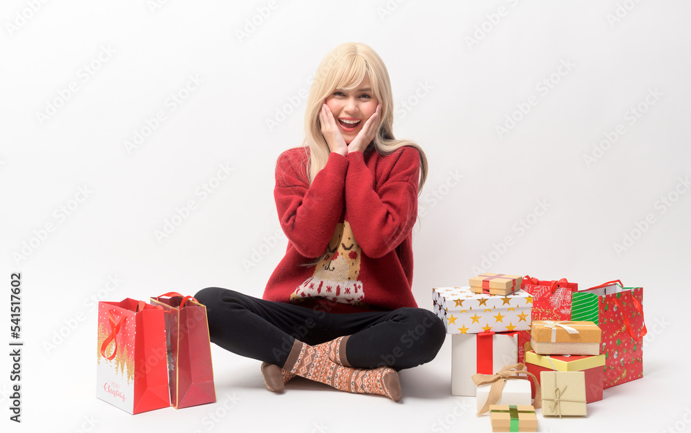Portrait of happy Caucasian young woman in in Christmas sweater with gift box and shopping bags over white background Portrait of happy Caucasian young woman in in Christmas sweater with gift box and shopping bags over white background
