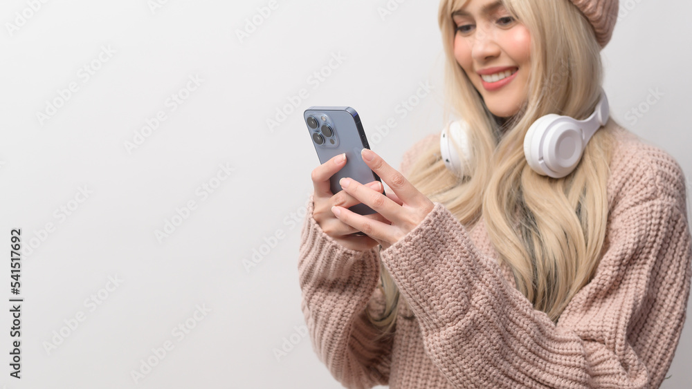 Portrait of Caucasian young woman wearing sweater holding smart phone over white background Portrait of Caucasian young woman wearing sweater holding smart phone over white background