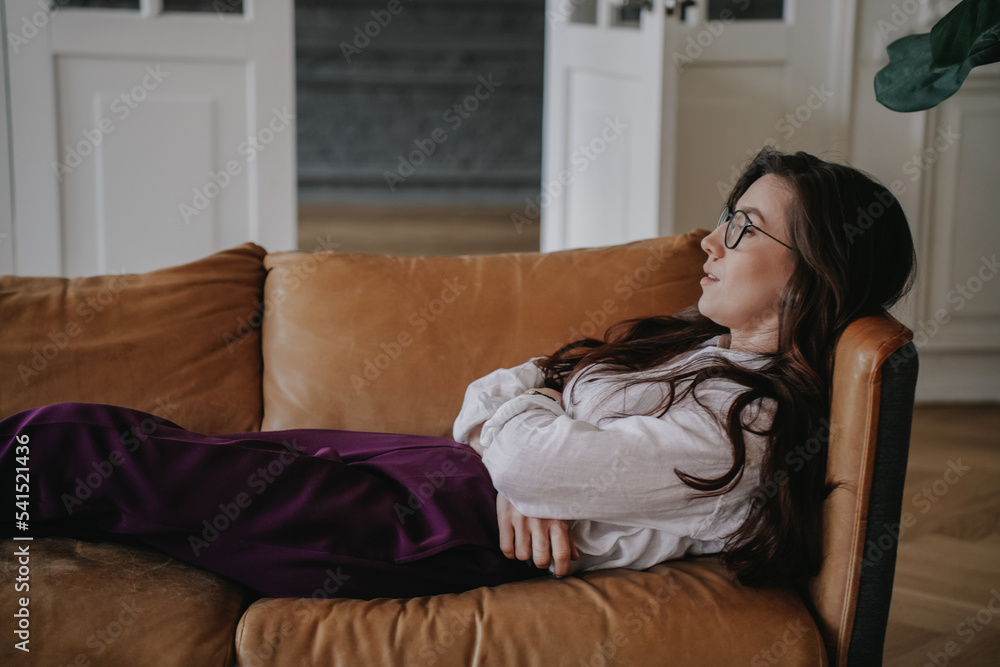 Frustrated young brunette in glasses, white shirt and violet pants laying on leather sofa at office, upset, entrepreneur have problems with business. Student woman sleepy, overloaded. Fatigue concept. Frustrated young brunette in glasses, white shirt and violet pants laying on leather sofa at office, upset, entrepreneur have problems with business. Student woman sleepy, overloaded. Fatigue concept.