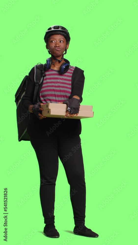 Vertical video: Food delivery courier holding boxes of pizza to give takeaway order, full body greenscreen. Woman carrying thermal delivery backpack and packages of fastfood, green screen backdrop. Vertical video: Food delivery courier holding boxes of pizza to give takeaway order, full body greenscreen. Woman carrying thermal delivery backpack and packages of fastfood, green screen backdrop.
