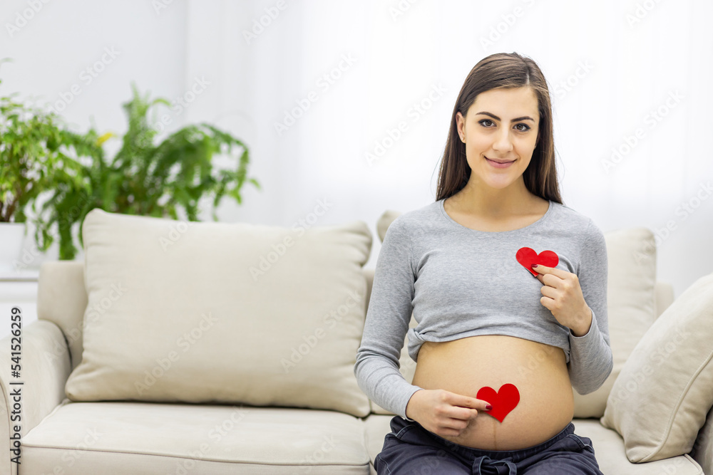 Photo of pregnant woman holding red heart in hands. Photo of pregnant woman holding red heart in hands.