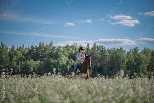 Portrait of a young beautiful dark-haired girl riding a horse on a summer day. © shymar27