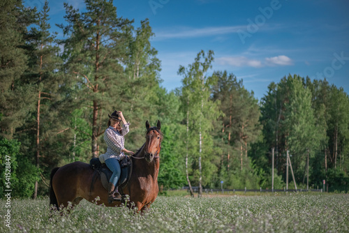 Portrait of a young beautiful dark-haired girl riding a horse on a summer day.