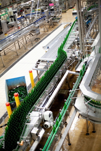 Beer factory bottles on the line. Technological line for washing of glass bottles for beer. High-tech line at the plant for the production of low alcohol drinks. On the conveyor are glass, green beer.