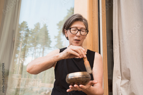senior asian woman with singing bowl in hands